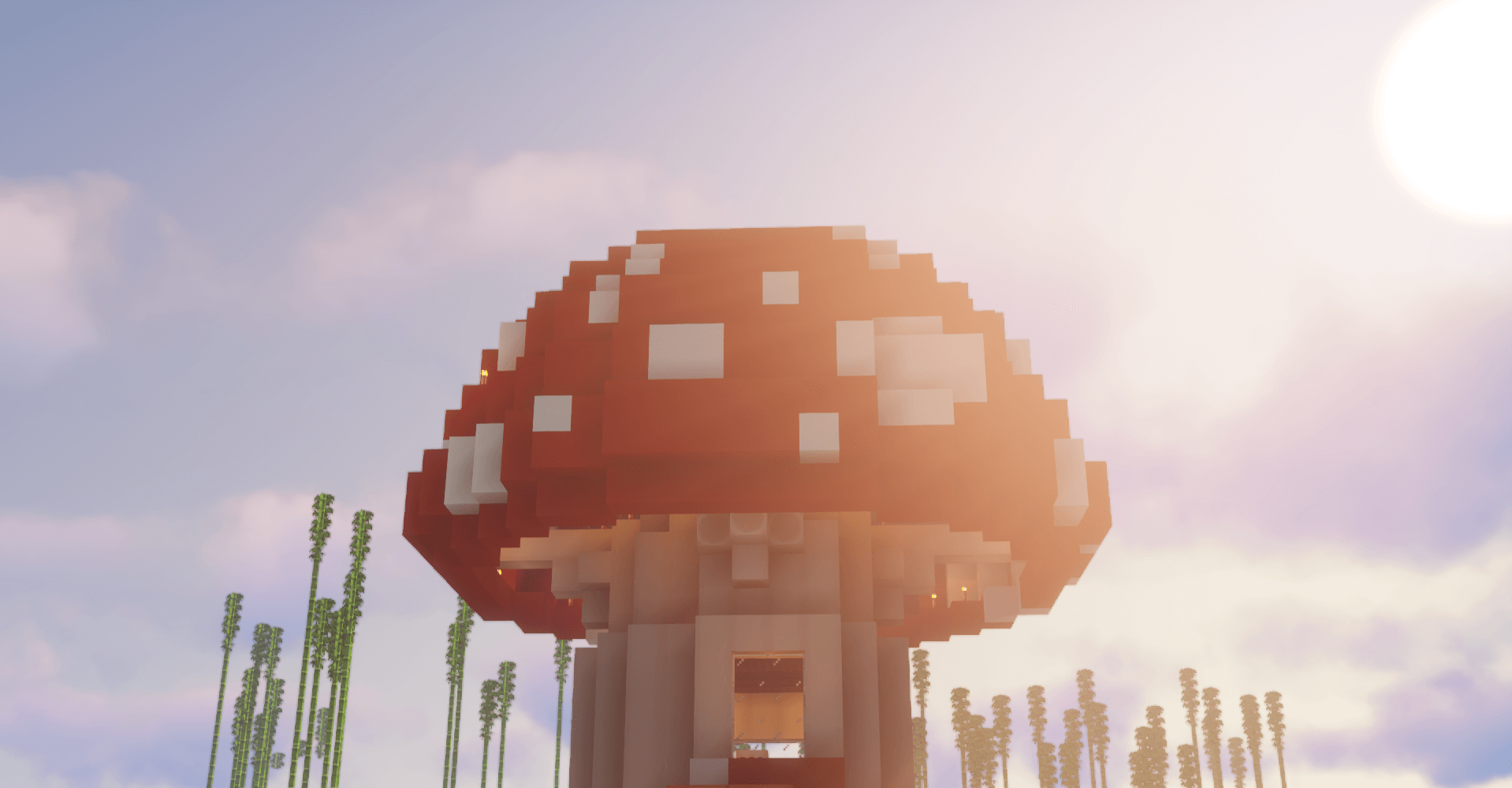 A giant red mushroom house rising above bamboo in bright sun flare.